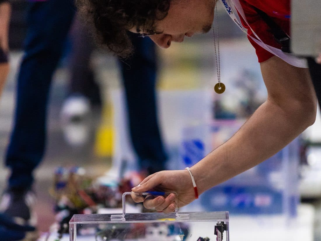Student adjusting their robot on the competition table